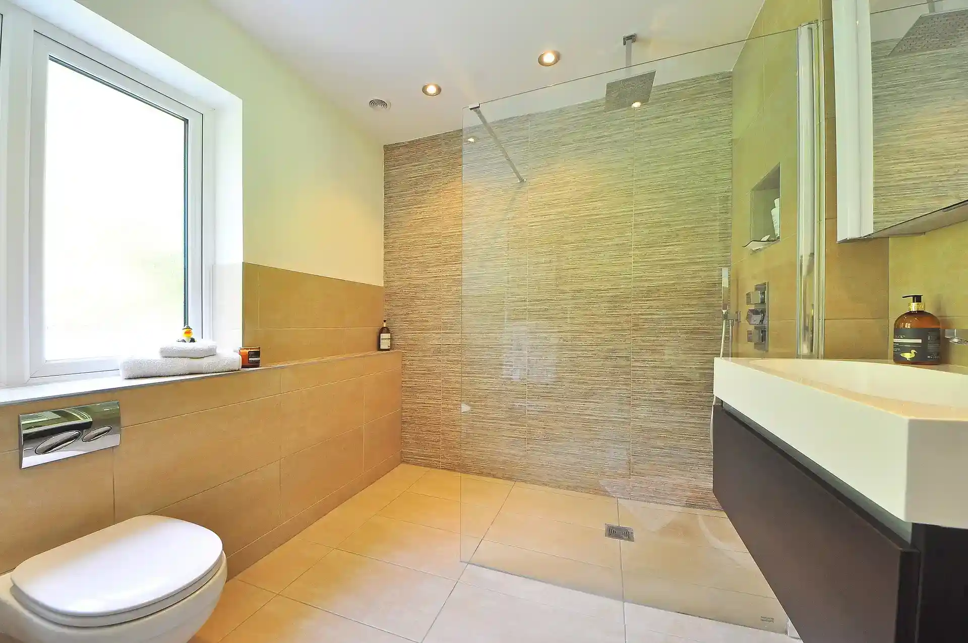 Beige travertine-look floor and wall tiles in a modern bathroom with walk-in shower
