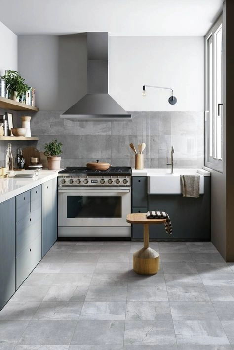 Gray concrete-look porcelain floor tiles in a modern kitchen with slate-blue lower cabinets
