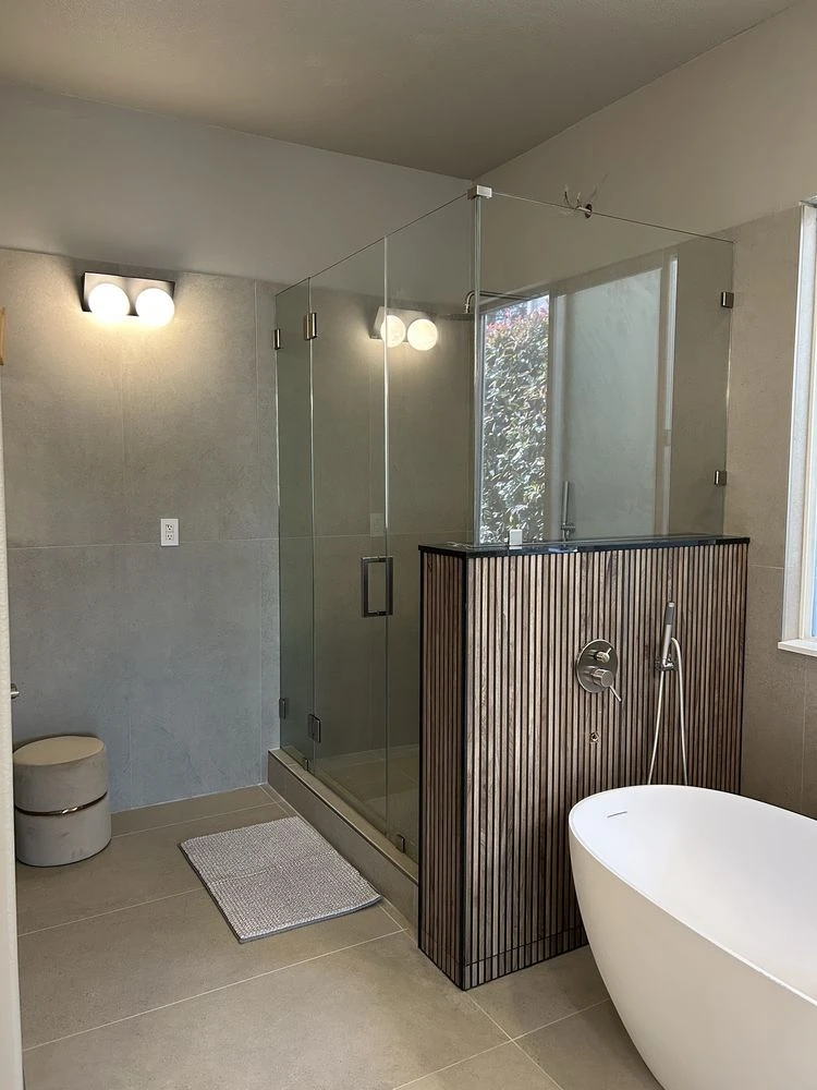 Warm beige travertine-look wall and floor tiles in a spa-style bathroom with floating shelves and plants
