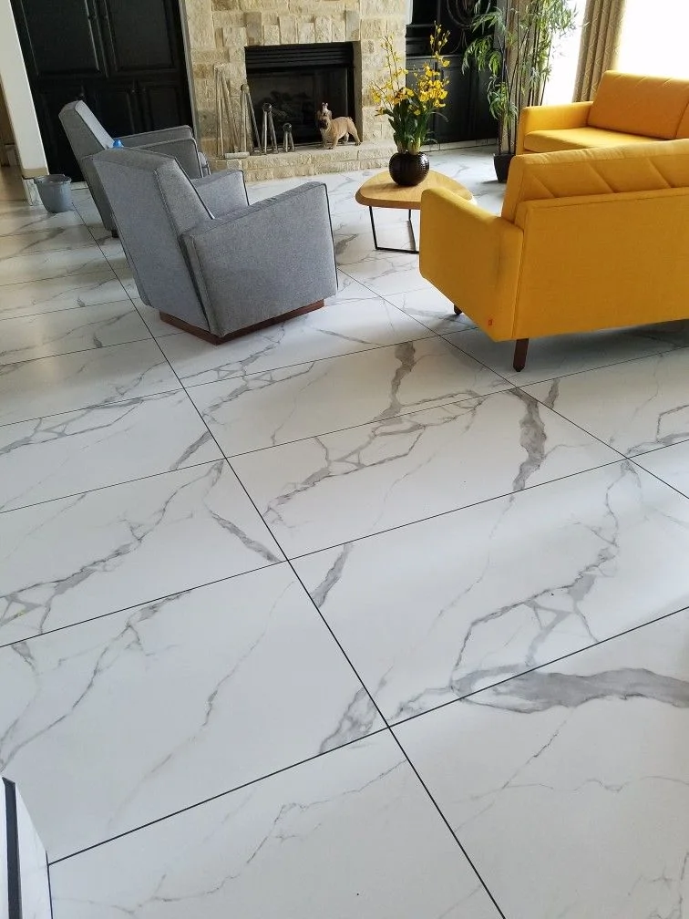 Glossy white marble-look porcelain floor tiles in a living room with bold yellow sofa
